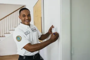Greg, a One Hour Conditioning Tech, looking at camera as he works on a smart thermostat