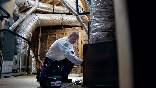 One Hour AC Tech kneeling, working on a furnace in an attic at a home in Lakeland, FL